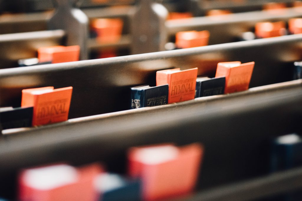 Close up image of pews in a church with Bibles and Hymns on then