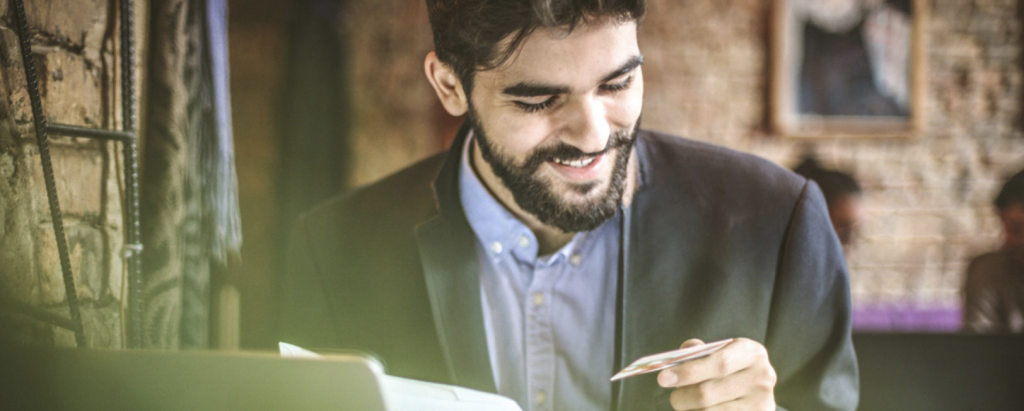 man in a cafe smiling at his business card