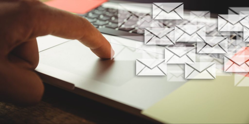 Composite image of hand using laptop put on a desk with letter icons