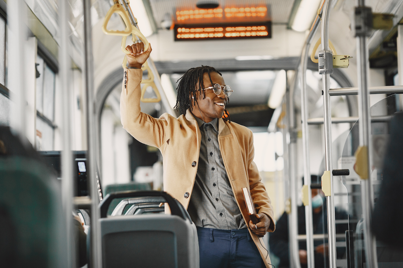 African American man riding in the city bus. Guy in a brown coat. Man with notebook.